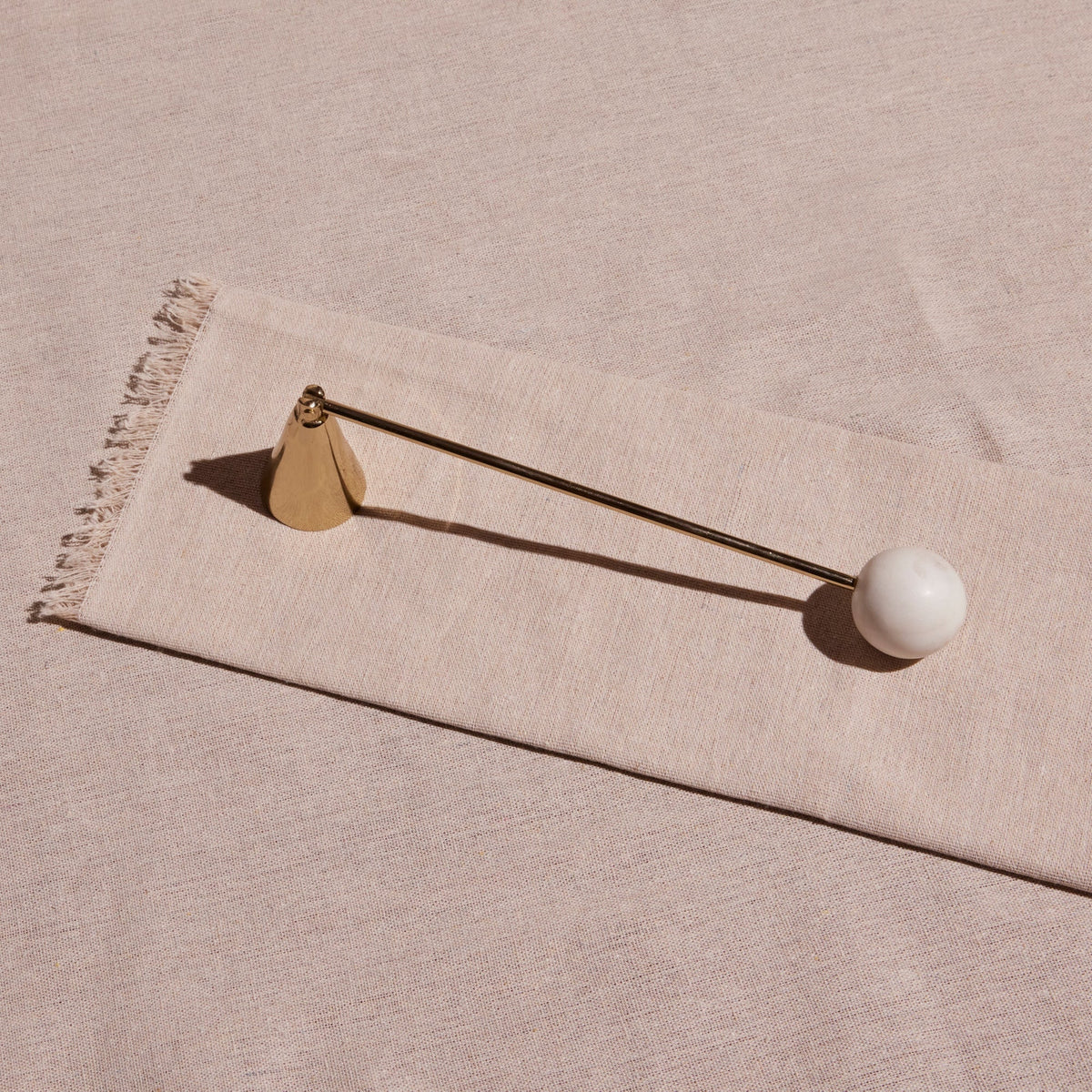 Brass-finish candle snuffer with a white marble base