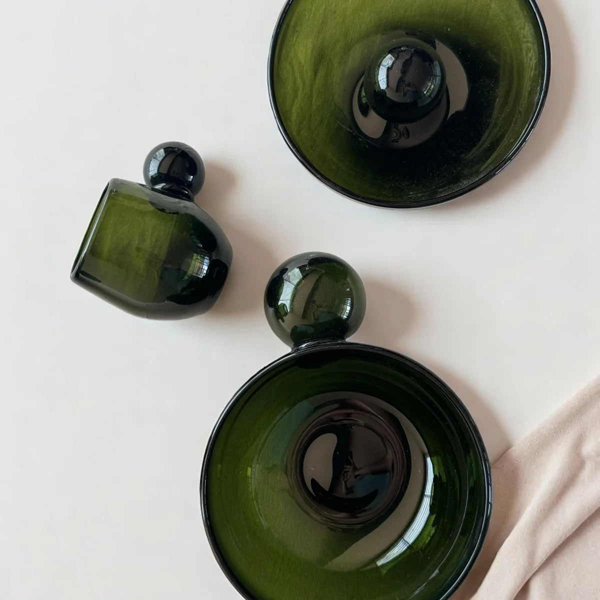 Three green glass vessels on a light white background